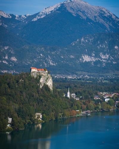 A stunning vertical shot of Bled Castle atop a cliff by Lake Bled with the Julian Alps in Slovenia.