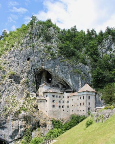 Free Explore the historic Predjama Castle built into the cliffs of Slovenia, surrounded by lush nature. Stock Photo