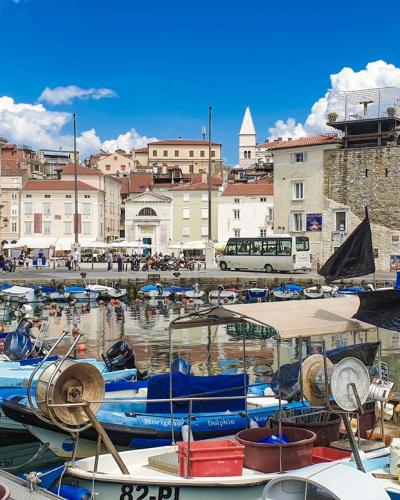 Vibrant harbor in Piran, Slovenia featuring boats and historic architecture under a clear blue sky.
